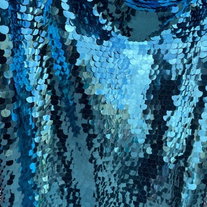 May include: Teal blue fabric with a scale-like pattern made of sequins.