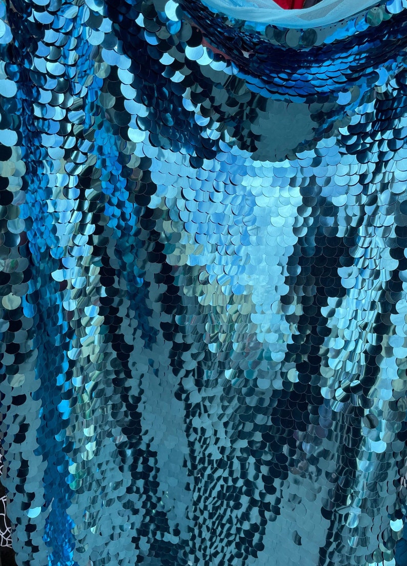 May include: Teal blue fabric with a scale-like pattern made of sequins.