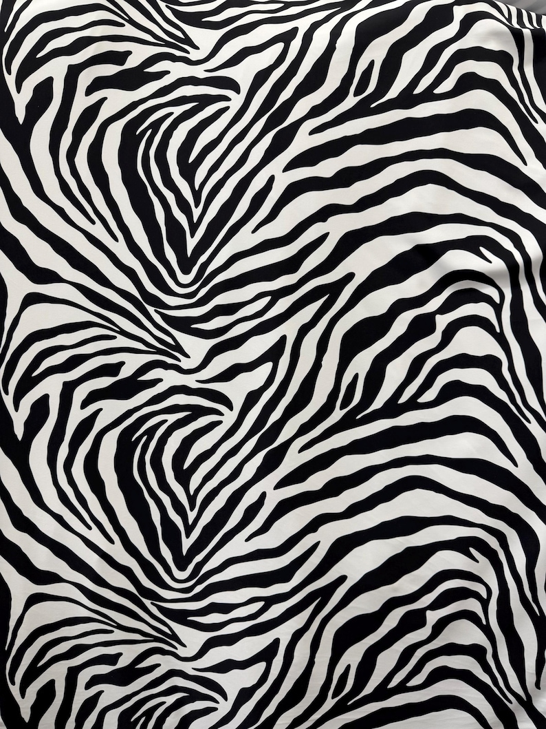 May include: Black and white zebra print fabric with a swirling pattern.