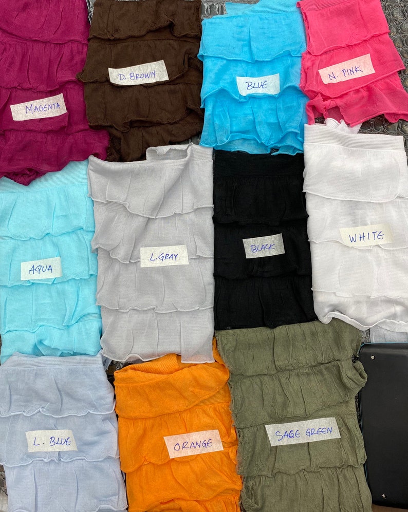 K&ouml;nnte beinhalten: Eine Sammlung von 12 Stoffproben in verschiedenen Farben, darunter Magenta, Braun, Blau, Rosa, Aqua, Hellgrau, Schwarz, Wei&szlig;, Hellblau, Orange und Salbeigr&uuml;n. Jede Probe ist mit einem Etikett mit dem Farbnamen versehen.