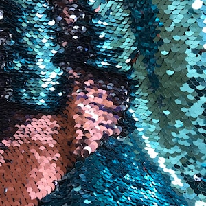 Puede incluir: Primer plano de una tela con lentejuelas turquesas y cobrizas. Las lentejuelas son redondas y se superponen, creando un efecto brillante. La tela parece ser de dos tonos, con &aacute;reas turquesas y cobrizas. La textura es suave y reflectante.