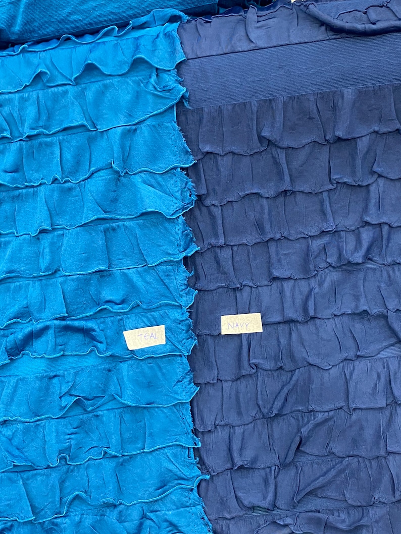 K&ouml;nnte beinhalten: Zwei Stoffproben, eine in Teal und eine in Marineblau, mit einer gekr&auml;uselten Textur. Die Proben sind mit "Teal" und "Navy" beschriftet.