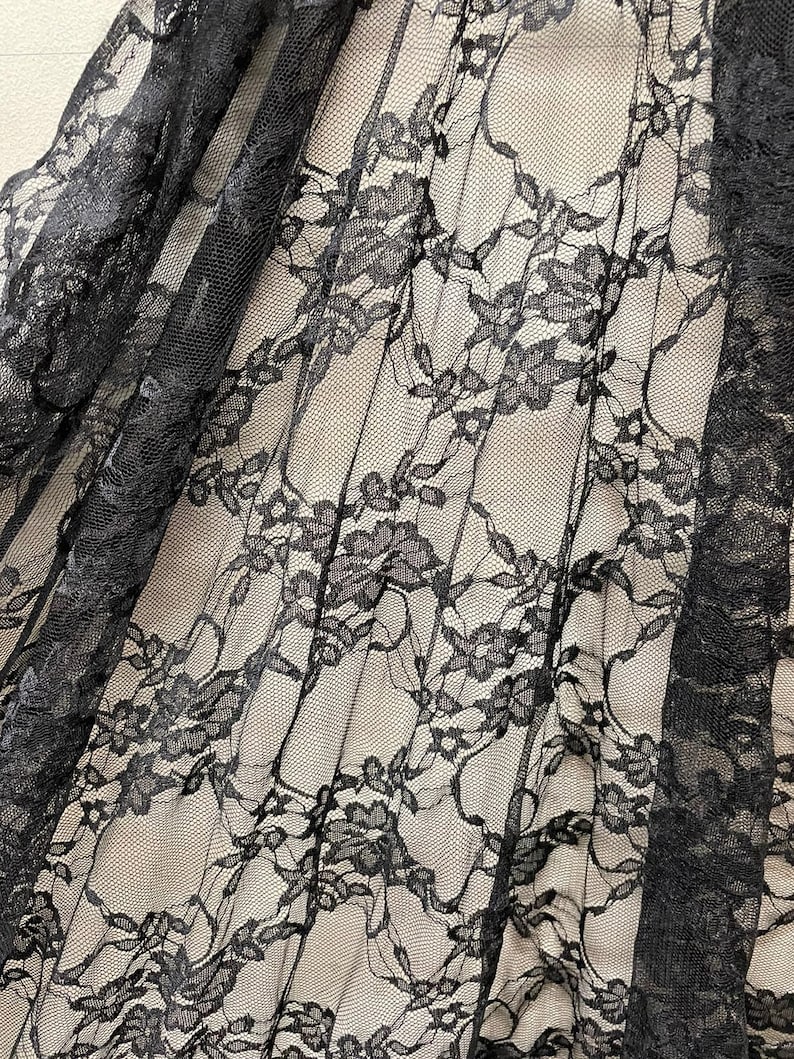 May include: Black lace fabric with a floral pattern. The lace is delicate and sheer, with a soft, flowing texture.