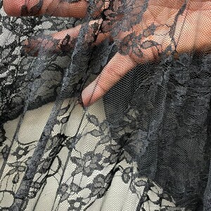 May include: Black lace fabric with a delicate floral pattern. The fabric is sheer and has a soft, flowing texture.