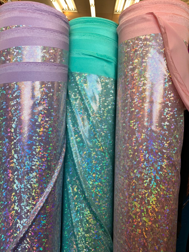 May include: Three rolls of iridescent fabric in lavender, teal, and pink. The fabric has a shimmery, holographic finish.
