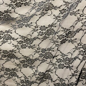 May include: Black lace fabric with a floral pattern. The lace is delicate and has a soft, flowing texture.