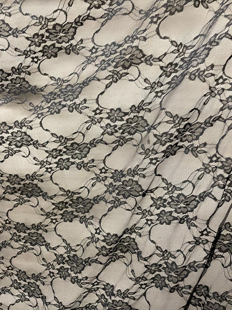 May include: Black lace fabric with a floral pattern. The lace is delicate and has a soft, flowing texture.