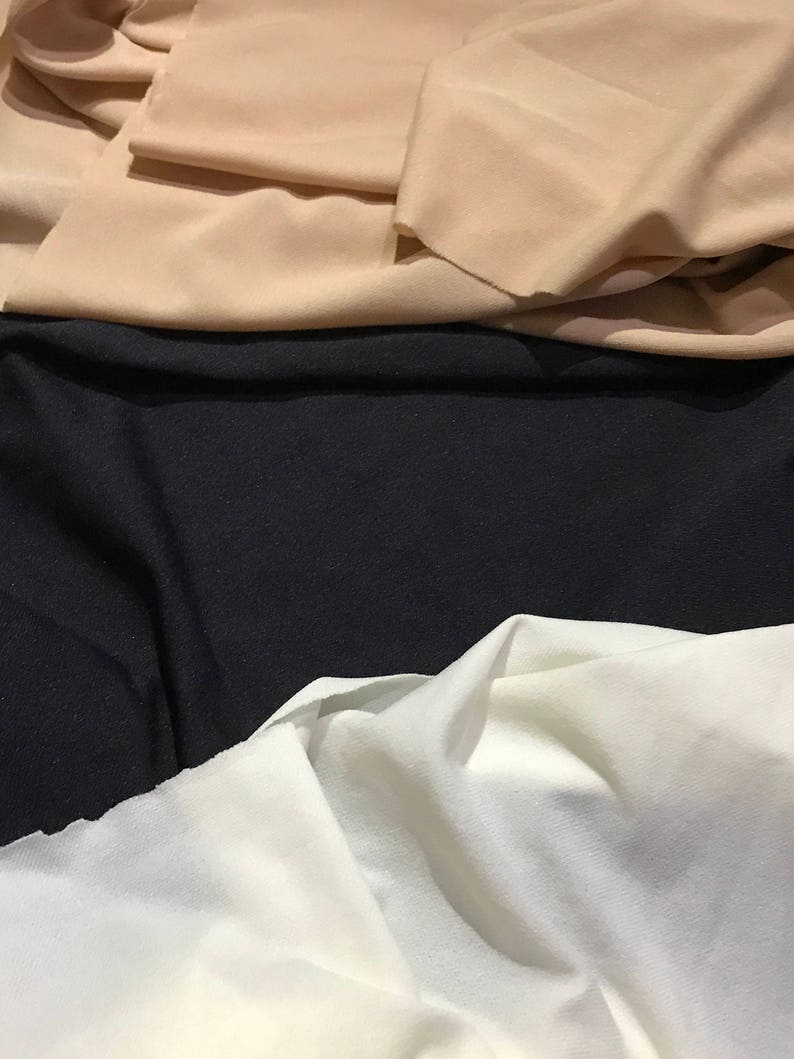 May include: Three fabric swatches in different colors: beige, black, and white. The fabric is smooth and has a slight sheen.