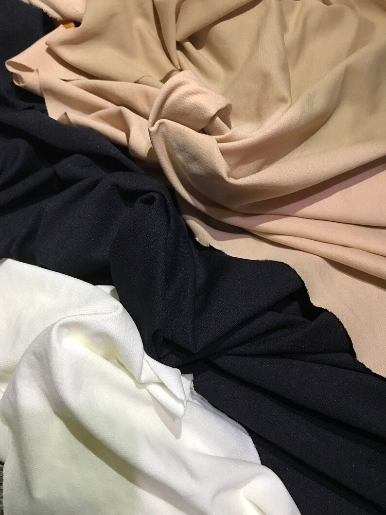 May include: Three fabric swatches in different colors: beige, black, and white. The fabric is soft and has a smooth texture.