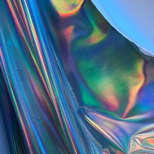 May include: A close-up of iridescent fabric with a blue, green, and purple colour scheme. The fabric is folded and has a smooth, shiny surface.