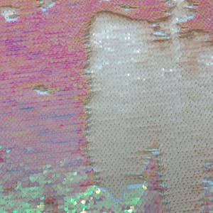 May include: Close-up of iridescent fabric with a white and green colour scheme. The fabric is made of sequins that are arranged in a pattern.