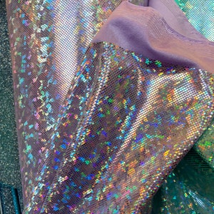 May include: Close-up of iridescent fabric with a textured, grid-like pattern. The fabric has a holographic finish with shades of blue, green, and purple.