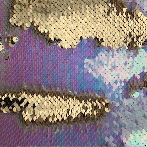 May include: Close-up of iridescent purple, blue, and white sequins with gold sequins in the background.