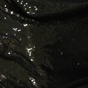 May include: Black fabric with a subtle sheen, covered in small, round sequins.