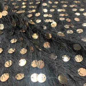 May include: Black fabric with gold sequins in a circular pattern. The fabric has a fuzzy texture.