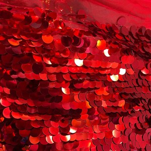 May include: Red sequin fabric with a shiny finish. The sequins are arranged in a scale-like pattern.