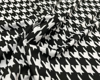 May include: Black and white houndstooth patterned fabric. The fabric is smooth and has a slight sheen.