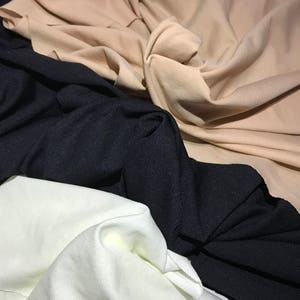 May include: Three fabric swatches in different colors: beige, black, and white. The fabric is folded and textured.