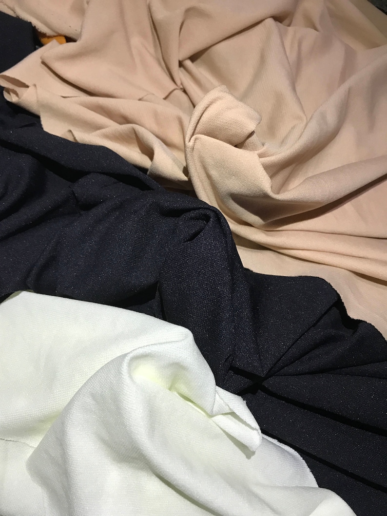 May include: Three fabric swatches in different colors: beige, black, and white. The fabric is folded and textured.