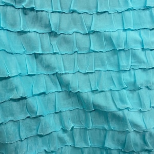 K&ouml;nnte beinhalten: Nahaufnahme eines hellblauen Stoffes mit einer gekr&auml;uselten Textur. Der Stoff ist aus einem weichen, leichten Material gefertigt und hat einen zarten, femininen Look.