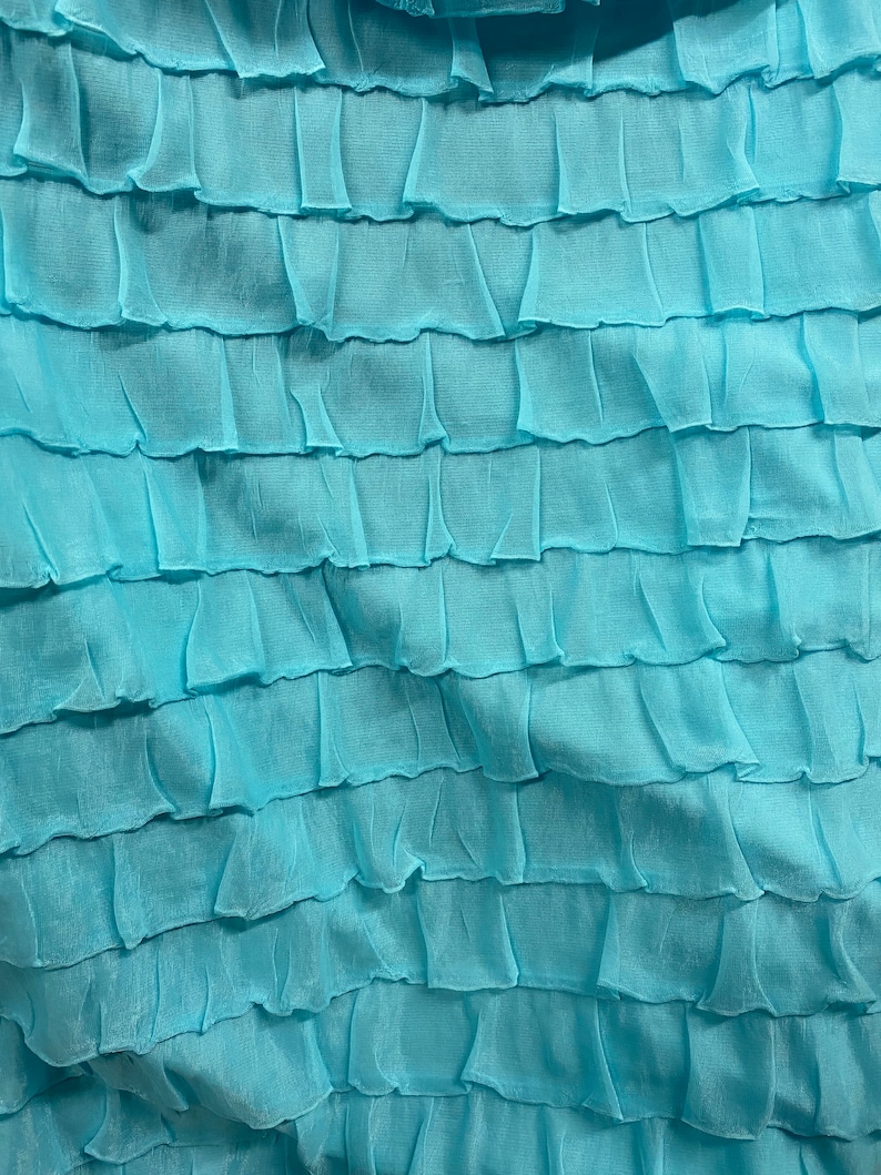 K&ouml;nnte beinhalten: Nahaufnahme eines hellblauen Stoffes mit einer gekr&auml;uselten Textur. Der Stoff ist aus einem weichen, leichten Material gefertigt und hat einen zarten, femininen Look.