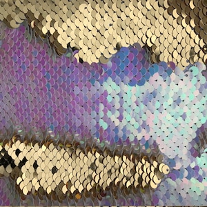 May include: Close-up of iridescent sequins in gold, purple, and blue colours. The sequins are arranged in a pattern of overlapping scales.