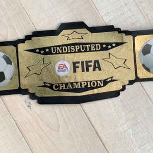 May include: A black and gold championship belt with the words "Undisputed FIFA Champion" and two footballs.