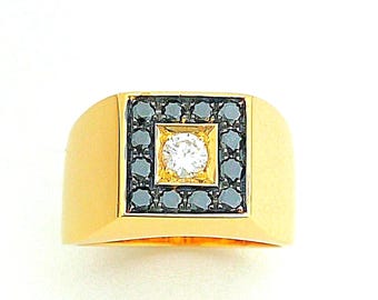 May include: A gold ring with a square face. The face features a central white diamond surrounded by a square of black stones, framed by a gold border. The band is a solid gold color.