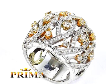 May include: A large, ornate ring with a silver band and intricate design. The ring features numerous small, clear stones and accents of gold-colored metal. The word "PRIMA" is visible in gold text at the bottom of the image.