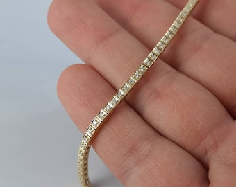 May include: A gold chain bracelet with small, clear diamonds set in a line along the length of the bracelet.