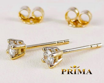 Puede incluir: Un par de pendientes de oro con gemas claras y brillantes. Los pendientes tienen un engaste clásico de cuatro puntas y se muestran con sus respaldos a juego. La palabra "PRIMA" está impresa en oro.