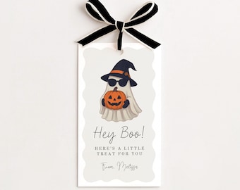 Op de afbeelding: Een rechthoekig cadeaulabel met geschulpte randen, voorzien van een witte geest met een zwarte heksenhoed en zonnebril die een oranje pompoen vasthoudt. De tekst luidt Hey Boo! HERE'S A LITTLE TREAT FOR YOU From. Melissa. Aan de bovenkant zit een zwart-wit lint vastgemaakt.