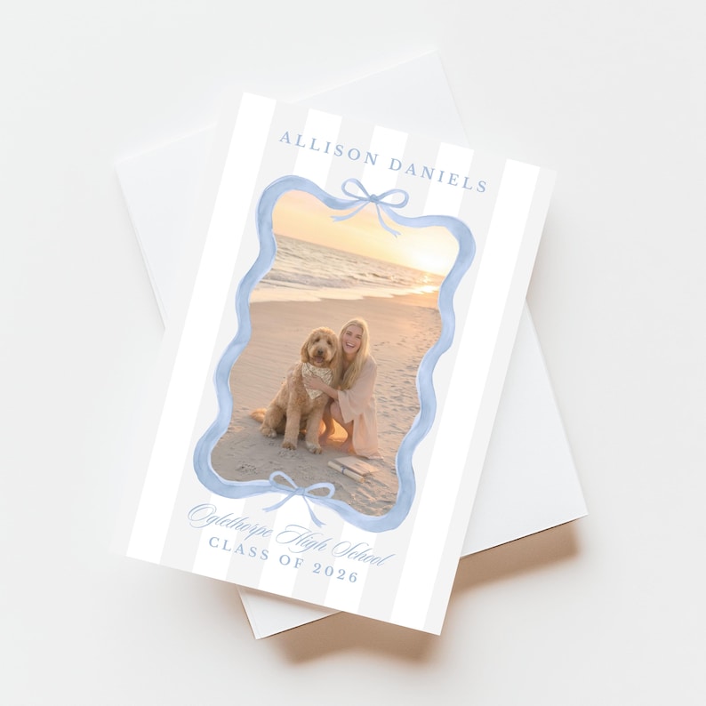May include: Graduation announcement card with a photo of a person and a dog on a beach. The card has a light blue scalloped border and bows. Text includes "Allison Daniels" and "Oglethorpe High School Class of 2026".