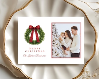 Könnte beinhalten: Eine Weihnachtskarte mit einem Aquarellkranz und einer roten Schleife sowie den Worten "FRÖHLICHE WEIHNACHTEN". Auf der rechten Seite ist ein Familienfoto eingerahmt. Die Familie versammelt sich um einen Weihnachtsbaum. Der Familienname und das Jahr sind ebenfalls enthalten.