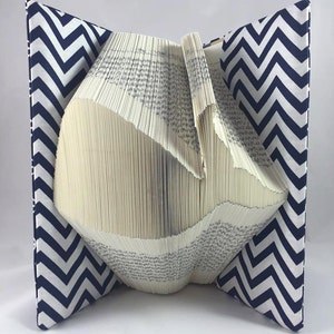 Puede incluir: Un libro doblado en forma de ballena, con una cubierta de tela con estampado de chevron azul marino y blanco.