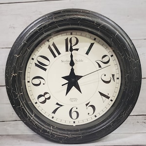May include: Black and white clock with a distressed black frame. The clock face has a white background with black Roman numeral hour markers and black hands. The clock face also has the text "Sterling Noble Clock Company" and "Registration No. 1001717 Mfg. No. 9".