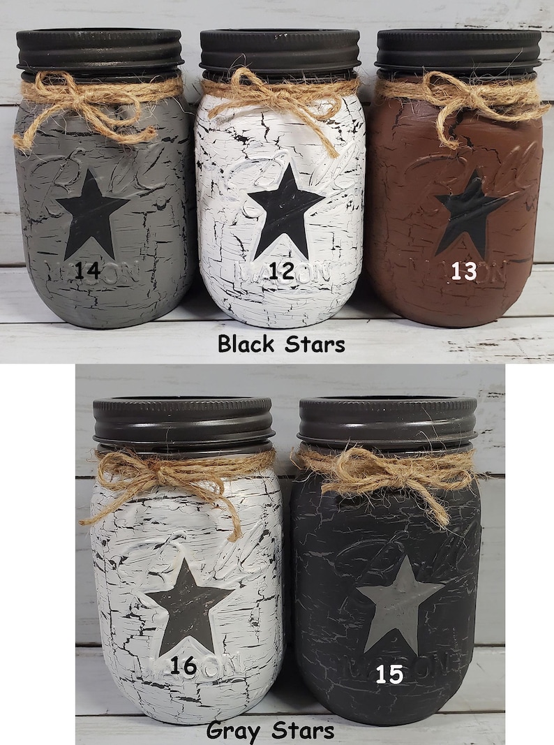 May include: Set of six mason jars with distressed paint and star designs. Three jars have black stars and the numbers 12, 13, and 14. Three jars have gray stars and the numbers 15, 16. Black Stars and Gray Stars.