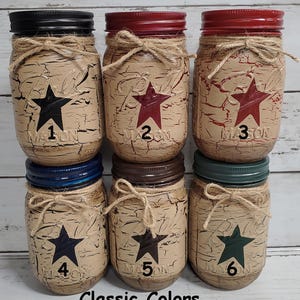 May include: Six mason jars with distressed paint and a star design in different colors. The jars are labeled with numbers 1 through 6. Classic Colors.
