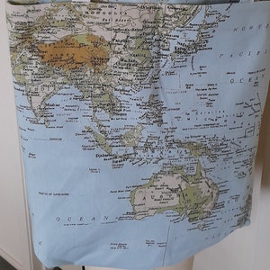 Könnte beinhalten: Eine hellblaue Tragetasche mit einem Weltkarten-Druck. Die Karte zeigt Kontinente in Grün und Blau, mit Ozeanen in Hellblau. Die Tasche hat zwei hellblaue Henkel.