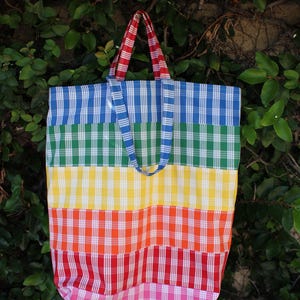 May include: A large, colorful tote bag with a rainbow plaid pattern. The bag has blue, green, yellow, orange, red, and pink stripes.