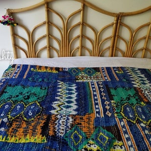 May include: A blue and green kantha quilt with a geometric pattern. The quilt is on a bed with a bamboo headboard.