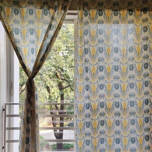Könnte beinhalten: Ein Paar gelbe und blaue gemusterte Vorhänge hängen an einem Fenster. Die Vorhänge sind aus einem leichten Stoff und haben ein geometrisches Muster.