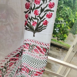 May include: White curtain with a floral design featuring pink flowers and green leaves. The curtain has a patterned border with red and black floral and geometric elements. The word "Brishtly" is visible in the image.