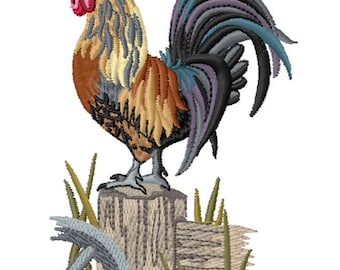 May include: An embroidery design of a rooster with a red comb and wattle, tan and brown neck feathers, and a dark gray and blue tail. The rooster stands on a textured wooden fence post surrounded by green grass and a gray wooden wheel.