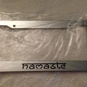 May include: Silver license plate frame with the word "namaste" engraved in black lettering.