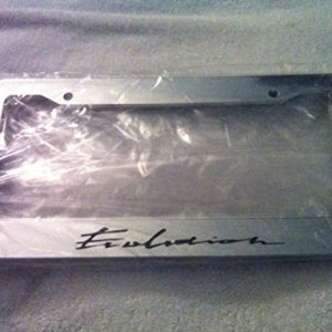 May include: Silver license plate frame with the word "Evolution" in black lettering.