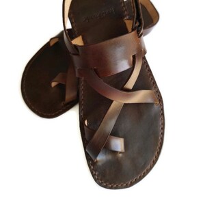 Op de afbeelding: Bruine leren sandalen met gekruiste banden en een gespsluiting.