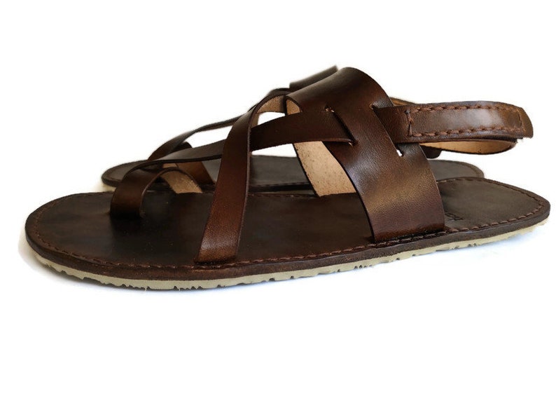 Op de afbeelding: Bruine leren sandalen met een gekruist bandontwerp en een achterband. De sandalen hebben een platte zool.