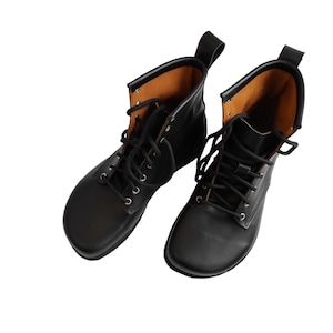 Puede incluir: Un par de botas de cuero negro con dise&ntilde;o de cordones. Las botas tienen punta redondeada y una leng&uuml;eta en la parte trasera. El forro interior es de color marr&oacute;n claro.