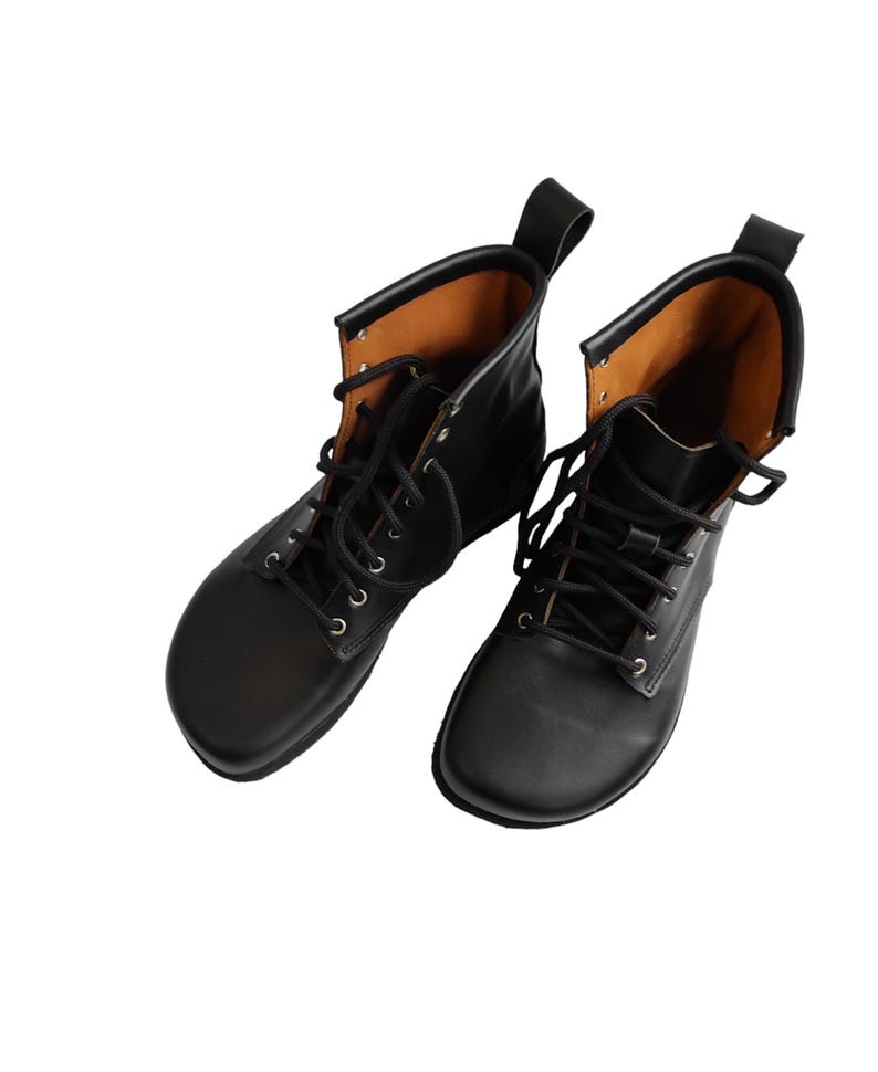 Puede incluir: Un par de botas de cuero negro con dise&ntilde;o de cordones. Las botas tienen punta redondeada y una leng&uuml;eta en la parte trasera. El forro interior es de color marr&oacute;n claro.